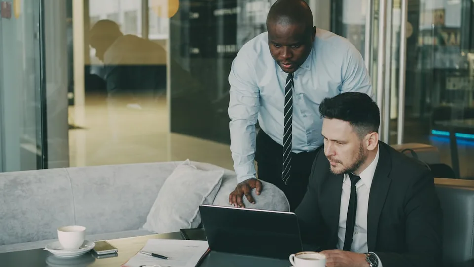 Two finance advisors collaborating over a laptop in a client meeting